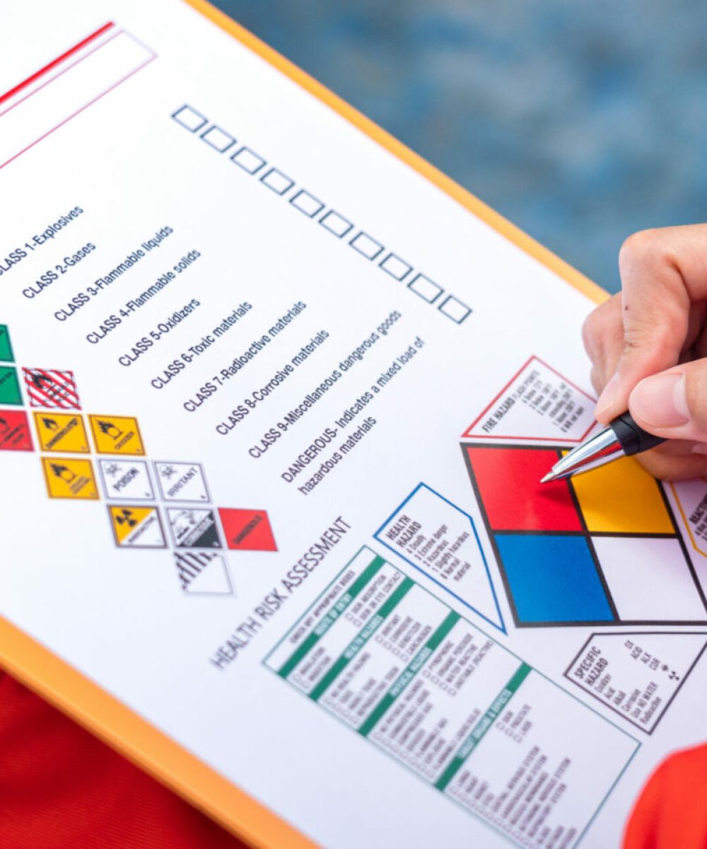 A safety engineer is using pen to rating the health risk assessment level of chemical hazardous material in the paperwork form. Industrial safety working scene, close-up and selecitve focus.